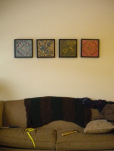 fabric framed in square black frames over the brown couch littered with tools and a measuring tape